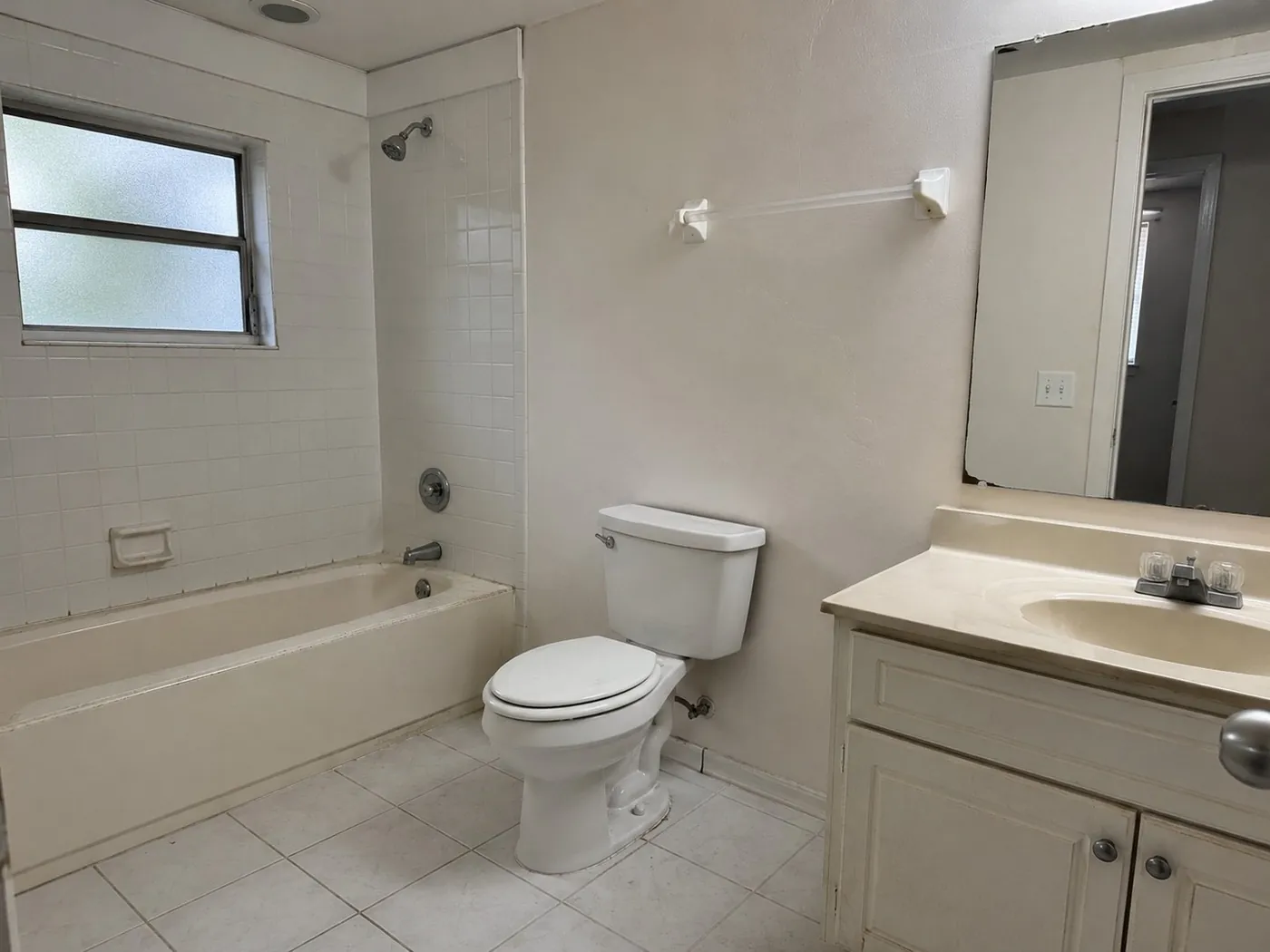 Dated bathroom with builder vanity and tub before the remodel