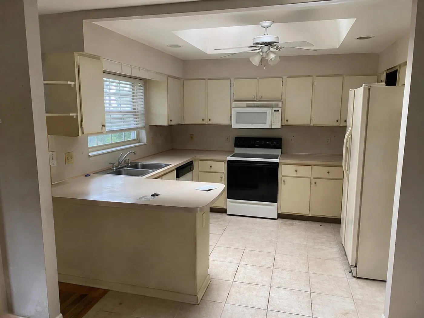 Dated kitchen with cream cabinets before the remodel